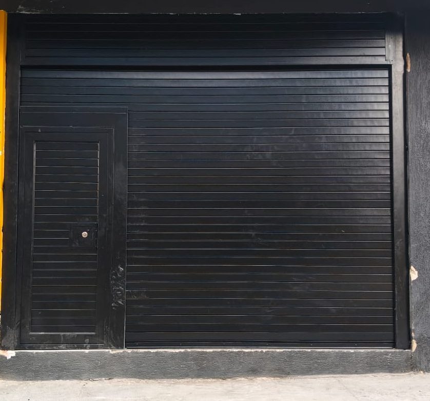 Cortina enrollable automática con puerta auxiliar fabricada en fleje de seguridad tipo americano, calibre 22 galvanizado, equipada con motor lateral Elite 611 para automatización. Garantizando seguridad, resistencia y funcionamiento práctico para accesos comerciales o industriales.
