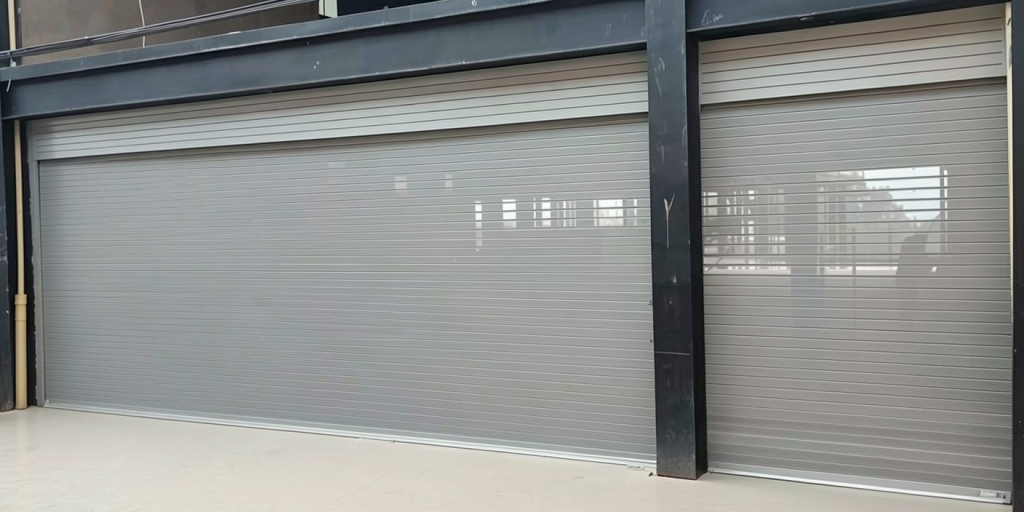 Cortina enrollable fabricada en fleje de seguridad tipo americano, calibre 22 galvanizado, con microperforado de 3 mm y acabado en pintura electrostática color gris. Incluye taparrollo interno y motor lateral para automatización, ofreciendo seguridad, durabilidad y un diseño moderno.